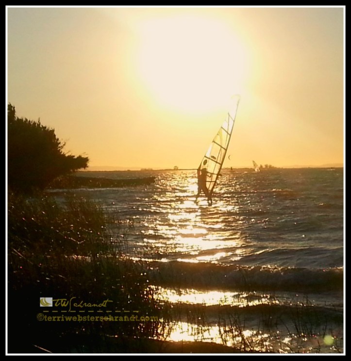 Summer Sun sets on windsurfer getting the last bits of wind.