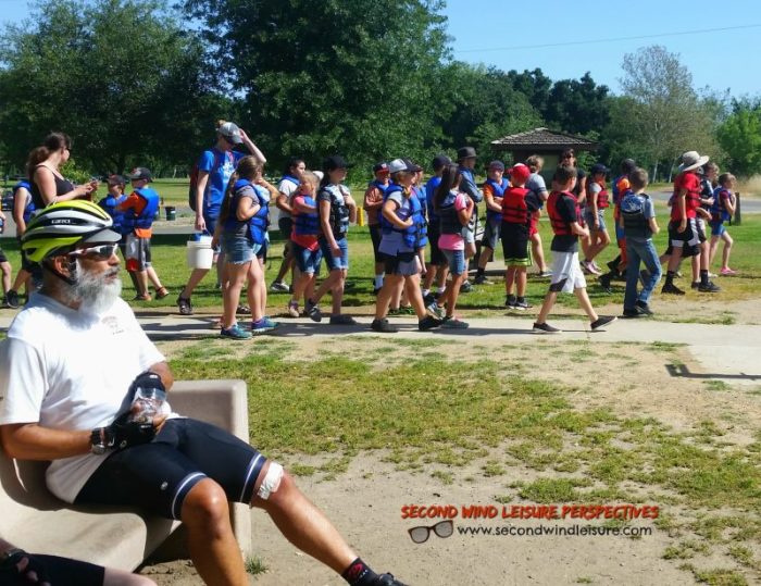 Middle School kids sporting their life jackets walk toward the river.