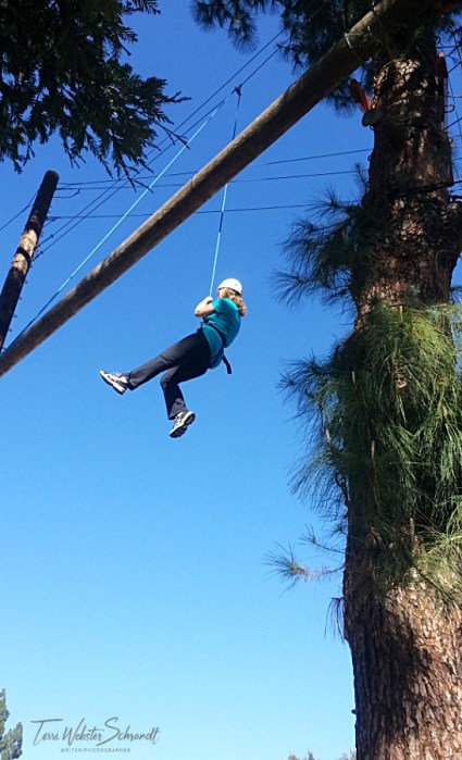 Woman hanging from harness from catwalk